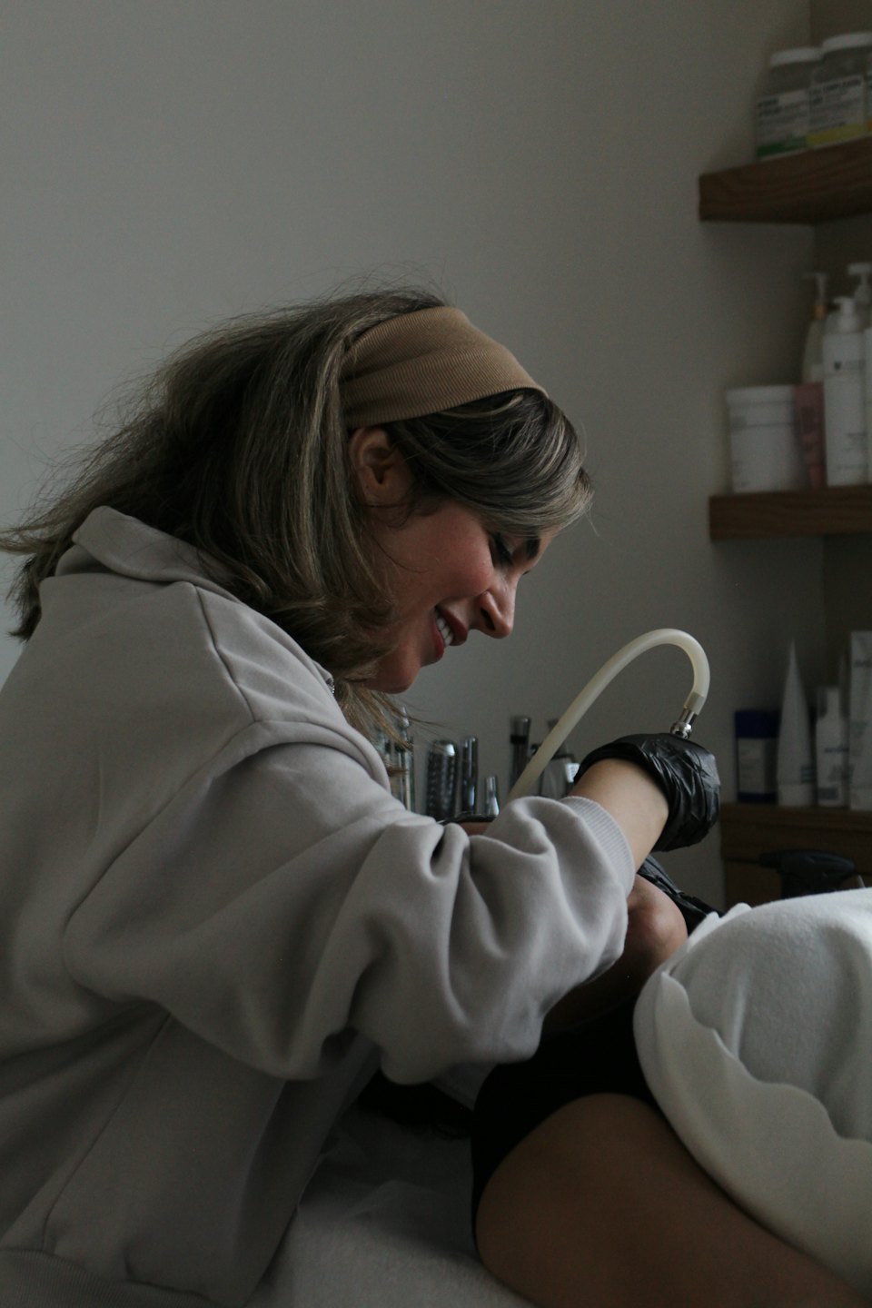 A technician wearing gloves performs a cosmetic treatment on a client.